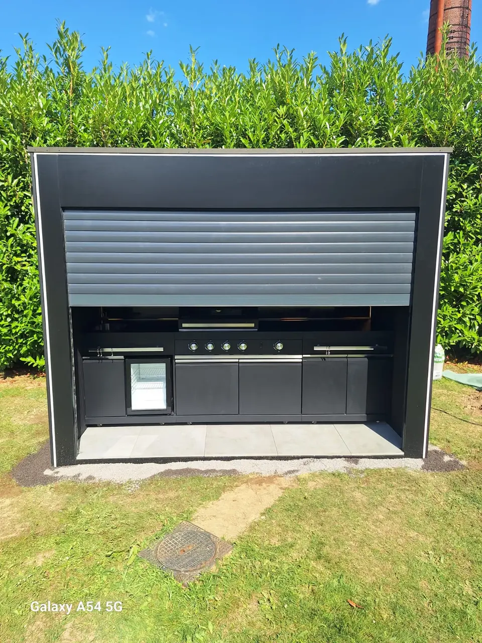 Outdoor-Küche mit teilweise geöffnetem Rollladen – No1Pool