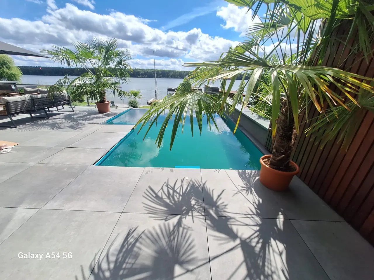 Poolterrasse mit Palmen und Blick auf das Wasser – No1Pool