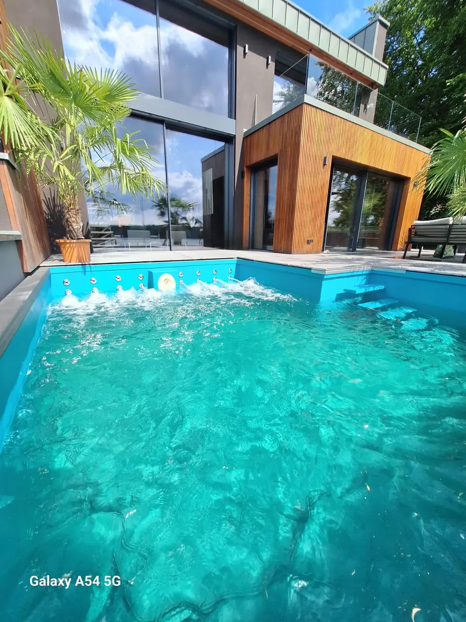 Sprudelnde Wasserfläche vor einem Holzgebäude – No1Pool